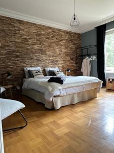 - une chambre avec un grand lit et un mur en briques dans l'établissement Au Ch'Alex, à Busset