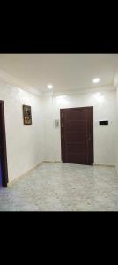 Großes Zimmer mit brauner Tür und Fliesenboden in der Unterkunft Résidence Abdel Rahman in Mostaganem