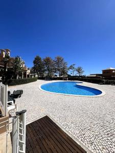 una gran piscina azul en un patio de piedra en Moradia Almorávia en Olhos de Água