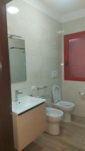 een badkamer met een wastafel, een toilet en een spiegel bij Villa Casaluce con giardino a 5 minuti dalle spiagge in Porto Cesareo