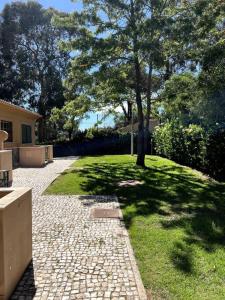 un jardin avec un arbre et une passerelle en briques dans l'établissement Moradia Almorávia, à Olhos de Água
