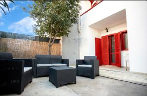 een patio met stoelen en tafels en een rode deur bij Villa Casaluce con giardino a 5 minuti dalle spiagge in Porto Cesareo