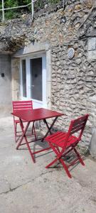 - deux tables de pique-nique rouges devant un bâtiment en pierre dans l'établissement Le Cocon Troglodyte, à Saint-Étienne-de-Chigny