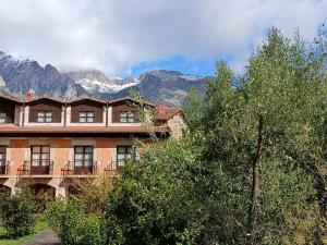 een gebouw met bomen en bergen op de achtergrond bij Picos de Europa Suites and Rooms in Turieno