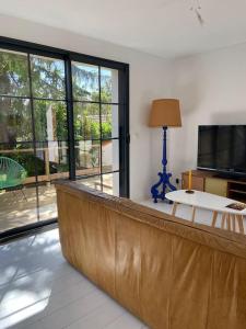 a living room with a leather couch and a television at Maison COSY proche centre et plages 7 couchages in Vaux-sur-Mer +22 photos