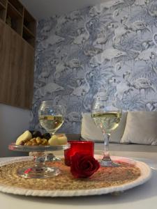 twee glazen witte wijn en een roos op tafel bij Apartments Tijana in Budva