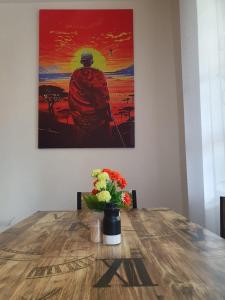 uma mesa com um vaso de flores e uma pintura em Novel 1-Bedroom in Madaraka Estate, Nairobi em Nairobi