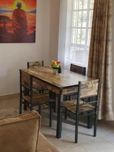 una mesa de madera y sillas en la sala de estar. en Novel 1-Bedroom in Madaraka Estate, Nairobi, en Nairobi