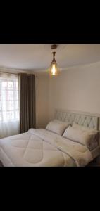 um quarto com uma grande cama branca e uma janela em Novel 1-Bedroom in Madaraka Estate, Nairobi em Nairobi