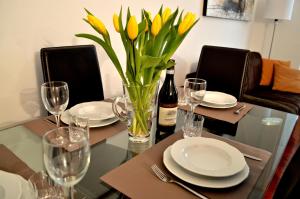 una mesa de comedor con una botella de vino y flores amarillas en La Casa Dei Viaggiatori en Milán