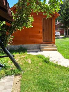 a wooden building with a door in the grass at Cabana Miska Chalet in Miercurea-Ciuc