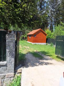 a small red shed in a yard with a fence at Cabana Miska Chalet in Miercurea-Ciuc