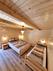 two beds in a log cabin bedroom with wooden ceilings at Cabana Miska Chalet in Miercurea-Ciuc