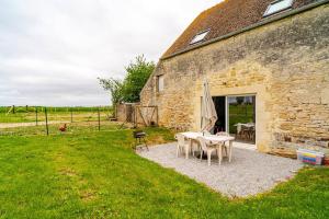 a stone building with a table and chairs and an umbrella at Gîte à la campagne Les Ch'tis Normands 