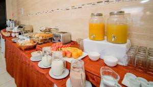a buffet with orange juice and food on a table at HOTEL GAVINA EXPRESS IQUIQUE in Iquique