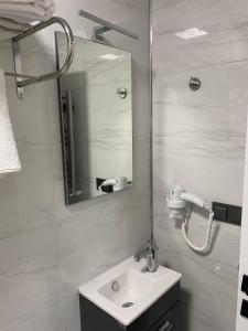 W białej łazience znajduje się umywalka i lustro. w obiekcie Aslan Airport Hotel w mieście Arnavutköy