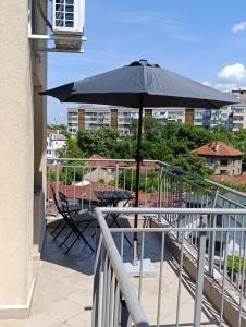 uma mesa com um guarda-chuva numa varanda em Витски em Ruse