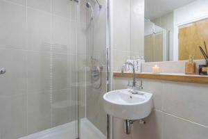 Un baño blanco con lavabo y ducha en Stylish 2 bedroom City Centre Apartment sleeps 6 with Free Convenient Bullring , Grand Central Parking, en Birmingham 18 fotos más