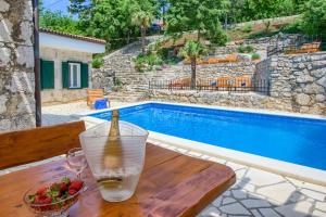 a drink on a wooden table next to a swimming pool at Villa Kirica in Bribir