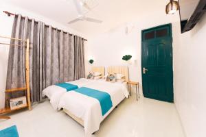 a bedroom with two beds and a green door at Fasdheythere Inn Maldives in Kendhoo