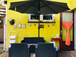 a table with an umbrella in front of a yellow wall at Éjjelibagoly Vendégház in Szentes