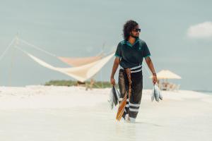 a man walking in the water on the beach at Fasdheythere Inn Maldives in Kendhoo
