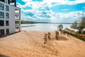 a building with a beach next to a body of water at Boszkowo Horizon Park in Boszkowo-Letnisko