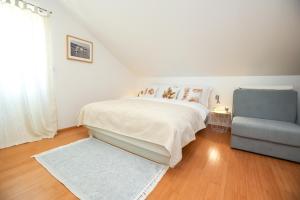 a white bedroom with a bed and a blue couch at Z&A Studio apartment with parking in Božava