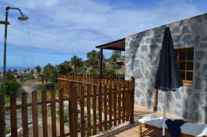 una casa con una valla de madera y una sombrilla en Galeón Ossorio Vistas Panoramicas, en Vallehermoso