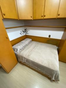 małe łóżko w pokoju z drewnianymi szafkami w obiekcie Quarto em Apartamento Amplo e Confortável w mieście Caxias do Sul