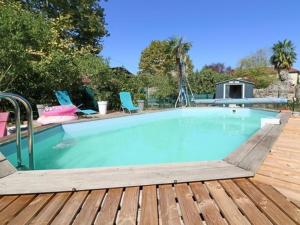 a large swimming pool on a wooden deck with chairs at Casa Di fiore in Maubourguet