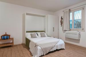 Un dormitorio blanco con una cama grande y una ventana en Tiny Oasis - Studio by the lake, en Toscolano Maderno