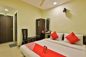 1 dormitorio con 1 cama grande con almohadas rojas en Collection O Hotel Santro en Naroda