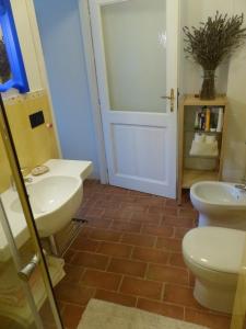a bathroom with two sinks and a toilet and a door at B&B Il vecchio pero in Capriglio
