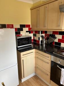a kitchen with a microwave and a refrigerator at Stylish 2 Bedroom Home In Essex in Basildon