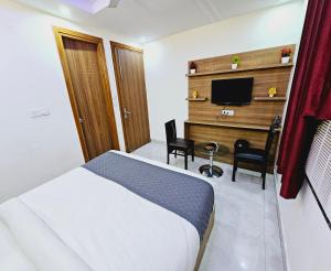 um quarto de hotel com uma cama e uma televisão em Hotel ALVAA GRAND Near Delhi Airport BY-AERO HOME STAY em Nova Deli
