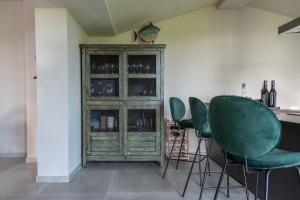 um bar com cadeiras verdes e um armário com copos de vinho em Casa Grotti: Charm & Comfort vicino al Mare em Capezzano Pianore,