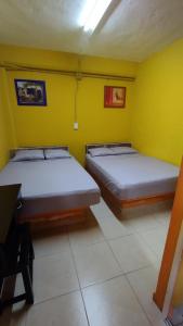 2 Betten in einem Zimmer mit gelben Wänden in der Unterkunft NovHotel in Comalcalco
