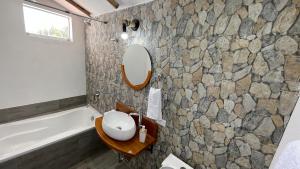y baño con bañera, lavabo y espejo. en Inca Allpa Home, en Huaran