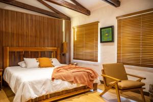a bedroom with a bed and a chair and windows at Villa Blanca Cloud Forest Hotel & Retreat in San Ramón