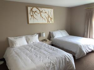 2 camas en una habitación de hotel con sábanas blancas en Hôtel Saint-Côme en Saint Come
