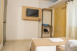 a room with two beds and a tv on the wall at Hotel Central in Sincelejo