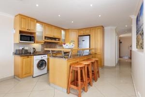 kuchnia z drewnianymi szafkami i blatem ze stołkami w obiekcie Lucien Sands 602 w mieście Margate