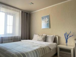 a bedroom with a bed with a flower picture on the wall at Seven City 24 in Semey