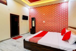 a bedroom with a brick wall and a bed with red pillows at Hotel Grand Village in Jhūsi