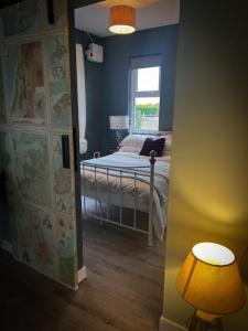 a bedroom with a bed with a lamp and a window at The Stables at Ballyward Croft in Ardkeen