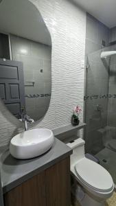 a bathroom with a sink and a toilet and a mirror at Suite 618 Downtown Guayaquil- Centro de la Ciudad in Guayaquil