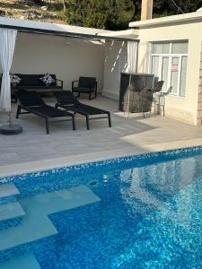 a swimming pool with chairs and a table next to a house at Mediterranean Jewel in Blato