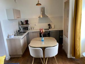 a kitchen with a table with a vase of flowers on it at Le Colibri - Domaine de la Houblette in Challans