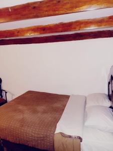 a bedroom with a bed with white sheets and a wooden beam at Casa Familiar El Carmen in Cusco